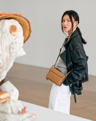 Woman holding a brown handbag with a neutral background