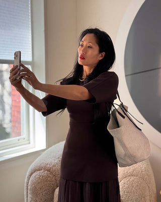 Woman taking a selfie in a room with a large round mirror and window.