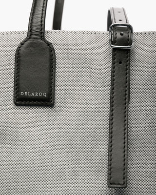 Gray tote bag with black leather strap and visible brand 'Delaroq' on a matching tag.