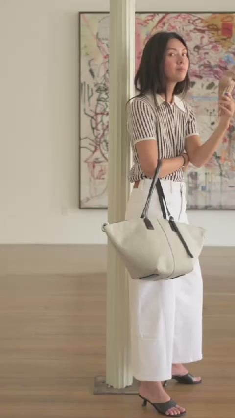 video of woman carrying concierge bags in an art gallery eating ice cream