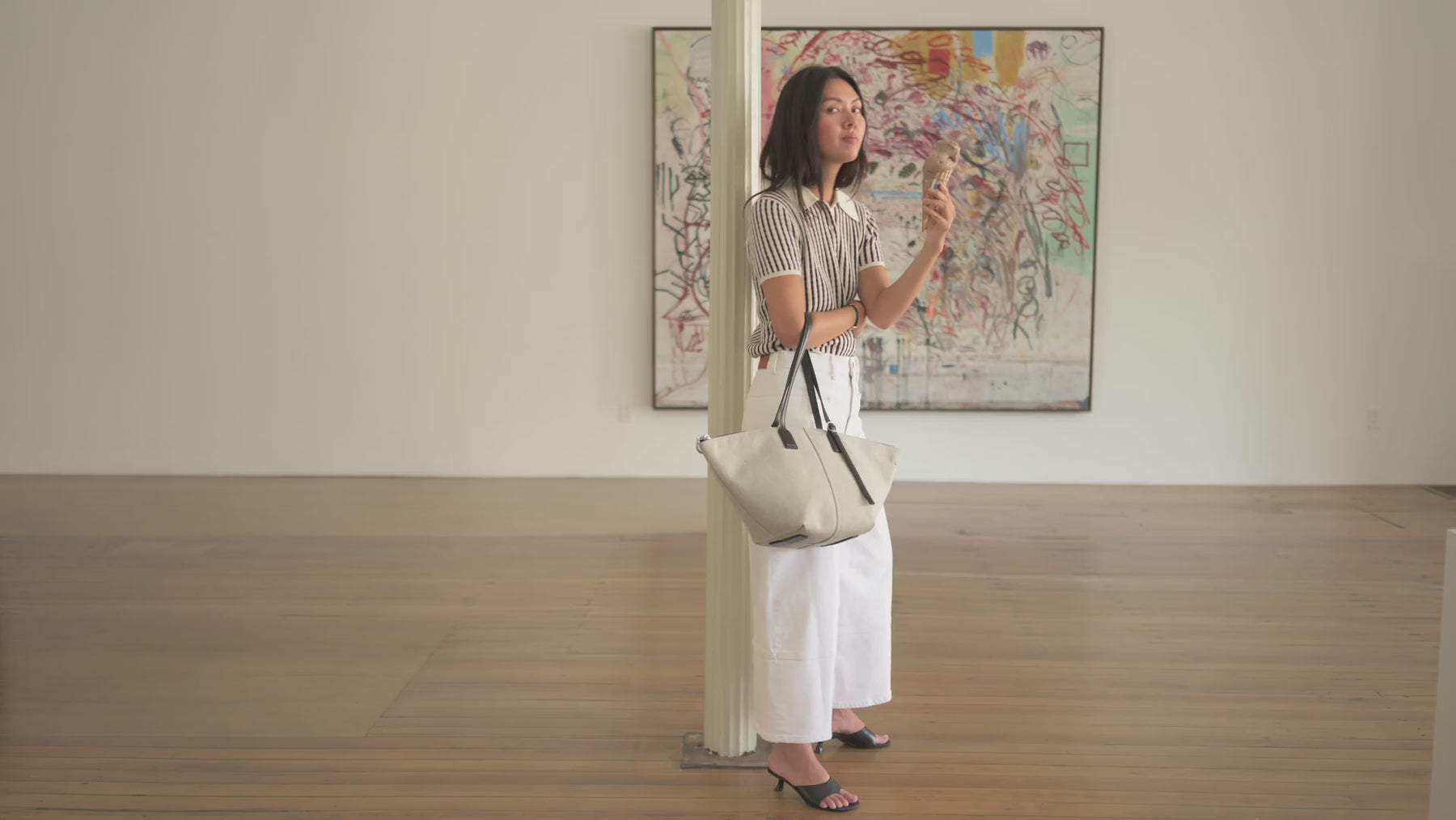 video composite of a woman wearing various Delaroq bags inside art gallery